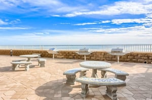 Stone tables and barbecue grills next to the beach at Romar Place