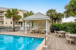 The clubhouse next to poolside chairs and tables at Gulf Island Condos