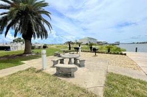 Barbecue grills and stone picnic tables next to the water at Jubilee Landing