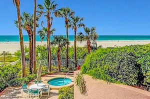 The outdoor hot tub amid tropical landscaping is near the beach.