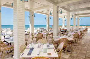The beachfront patio with dining tables and chairs