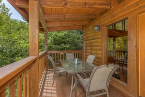 Outdoor dining for four on a covered deck at Cubs Crossing, a 3 bedroom cabin rental located in Gatlinburg