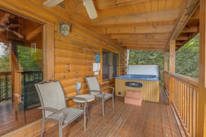 Two chairs, a table, and a hot tub on a covered deck at Cubs Crossing, a 3 bedroom cabin rental located in Gatlinburg