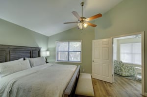 Unwind in the spacious primary bedroom with a king bed, vaulted ceiling, and serene natural light—your private retreat after exploring St. Simons Island.