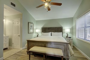 The serene king suite at 406 Harbour Oaks includes direct access to an en suite bathroom, plus soft lighting and windows on two sides for a calm, coastal feel.