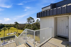 From this topfloor corner entry, enjoy elevated views of the pool, treetops, and nearby beach access path.