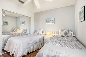 This guest bedroom includes two twin beds and a mirrored closet for storage, with the option to place the beds together for added flexibility.