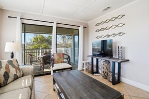 The living area features a TV and easy access to the balcony, creating a comfortable space to relax and enjoy the coastal setting.