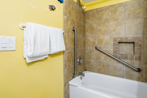 Tiled tub and shower combination with grab bars and builtin storage for added convenience.