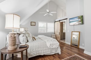 King bed, wallmounted TV, and a goldframed mirror — a bedroom that works equally well for adults who want to wind down in private.
