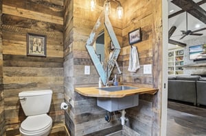 Reclaimed wood accent wall, floating vanity, vessel sink, and industrial pendant lights.
