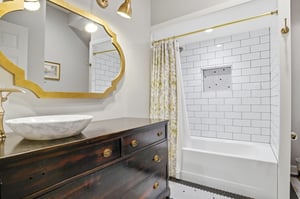 Dark wood vanity, vessel sink, gold hexagonal mirror, and white subway tile — this bathroom has a point of view.