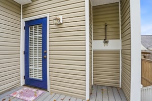 The back entrance detail — same confident blue door, exterior shutters, and a welcome mat that means what it says.