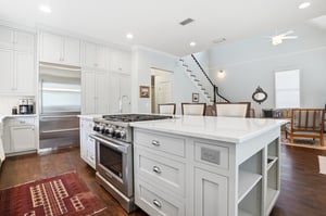 The island with pendant lighting and the staircase beyond — the whole main level visible from one vantage point.
