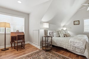 Vaulted ceilings, a ceiling fan, plantation shutters, and a Persian rug — the primary bedroom feels as large as it looks.