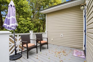 A shaded back deck with outdoor seating and a canopy of mature trees — where the afternoon goes once you decide to stay put.
