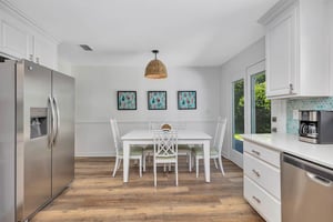 Main house dining area at 530 Delegal showing a dining table and seating, with windows providing natural light.