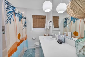 Hallway bathroom in the main house at 530 Delegal showing a tub and shower combination, single vanity with sink, mirror, lighting, and window with shade.