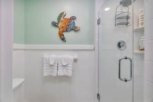 Guest house bathroom at 530 Delegal showing a walkin glass shower with tiled walls, builtin shelving, and towel storage.