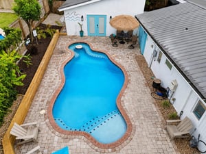 Overhead view of the heated pool at 530 Delegal showing paver deck, multiple lounge chairs, and the surrounding gated courtyard adjacent to the guest house.