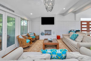 Main house living room at 530 Delegal showing multiple seating areas, fireplace, television, and large glass doors opening toward the screened in porch.