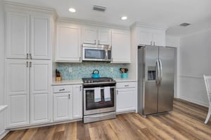 Main house kitchen at 530 Delegal showing fullsize appliances, extensive cabinetry, tile backsplash, and wood flooring adjacent to the living area.
