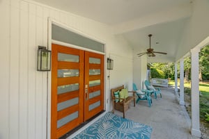 Front porch entry at 530 Delegal showing double front doors, covered porch seating, porch swing, and ceiling fan along the main house entry.