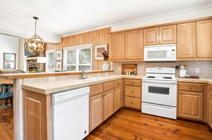Natural wood cabinetry and a broad breakfast bar keep the kitchen open to the living room and dining area.