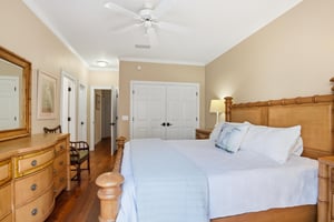 Second view of the main floor king primary suite showing the bed layout, hardwood floors, and easy mainlevel access.