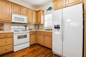 Kitchen angle showing the fullsize refrigerator, electric range, and wraparound cabinetry.