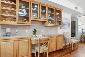 Builtin cabinet with glassfront storage, wine rack, and a small desk nook near the main living area.