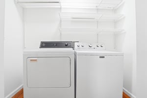 Fullsize washer and dryer inside the home with shelving above for longer stays.