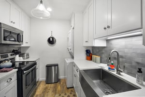 Kitchen with stainless appliances, subway tile, farmhousestyle sink, and full cookware setup.