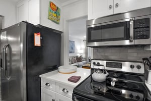 Kitchen angle showing fullsize appliances, microwave, refrigerator, and counter space.