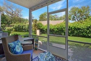 Screened patio with seating and a lawn view outside Ocean Walk J11.