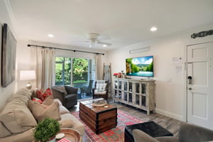 Living room view from the entry, with sofa seating, smart TV, and patio doors.