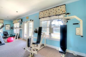 Fitness room with strength machines, mirrors, and open workout space.