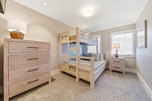 The upstairs bunk room sleeps three with a queen below, twin above, dresser and wallmounted TV.