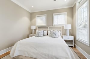 A straightforward bed view shows the generous scale of the suite, nightstands and windows on two walls.