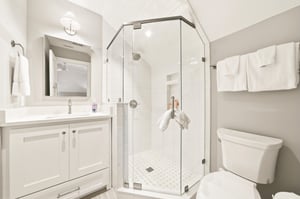 A glass shower, vanity storage and bright tile serve the second queen bedroom and bunk room.