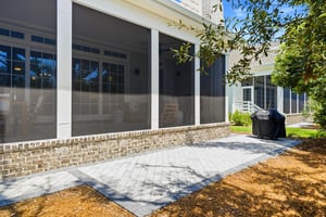 The grill sits on the paver patio just outside the covered outdoor dining and lounge areas.