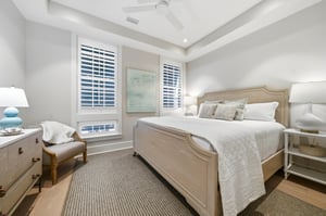 Palewood furnishings, a reading chair and tall windows fill the room.