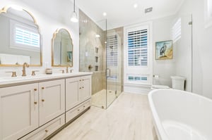 A freestanding bath and separate glass shower adjoin the downstairs primary bedroom.