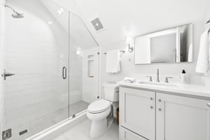 A glass shower, single vanity and chrome fixtures furnish this bathroom.