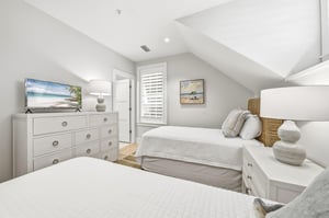 A dresser and television face the two beds.