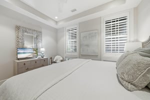 A matching dresser and shuttered windows face the bed.