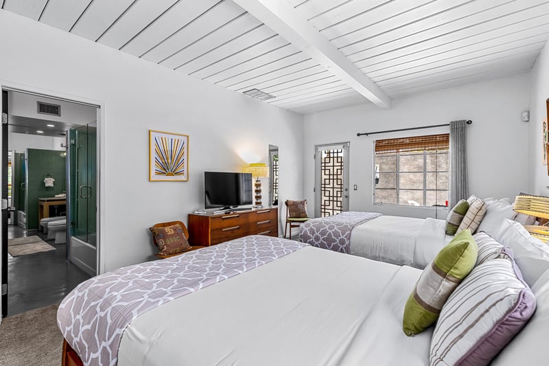 View of TV on dresser and private patio door from queen bed
