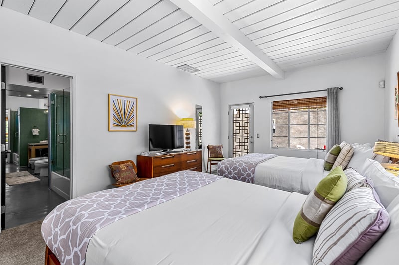 View of TV on dresser and private patio door from queen bed