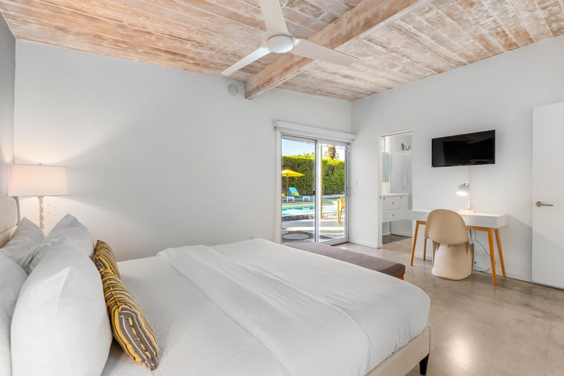 Relax in your serene bedroom with exposed wooden beams, modern amenities, and sliding doors opening to pool views.