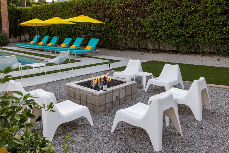 Gather around the cozy fire pit with modern seating, while colorful loungers and pool beckon nearby for ultimate relaxation.